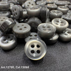 18L four hole plastic buttons in gray shade from Buttonology Inc pile on black fabric