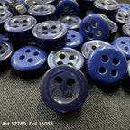 Close-up of 18L four hole plastic buttons in various shades of blue by Buttonology Inc