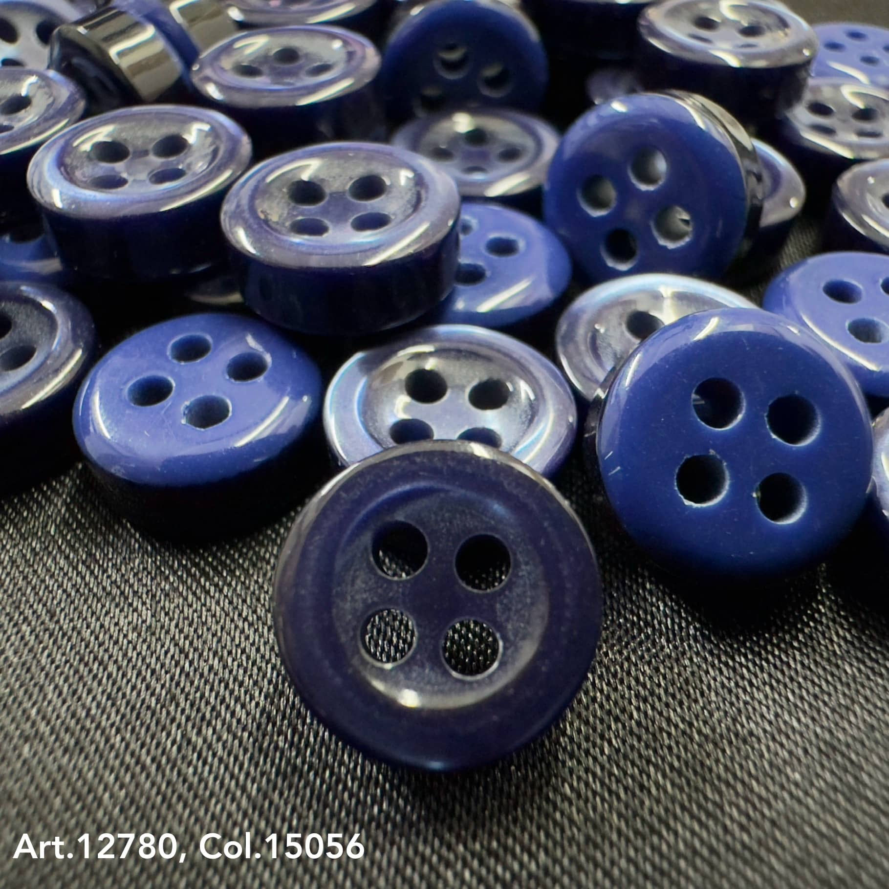 Close-up of 18L four hole plastic buttons in various shades of blue by Buttonology Inc