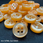 18L four hole plastic buttons in translucent orange by Buttonology Inc neatly arranged on dark fabric