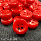 Bright red 18L four hole plastic buttons by Buttonology Inc on black fabric background