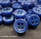 Close-up of blue 18L four hole plastic buttons scattered on fabric surface from Buttonology Inc