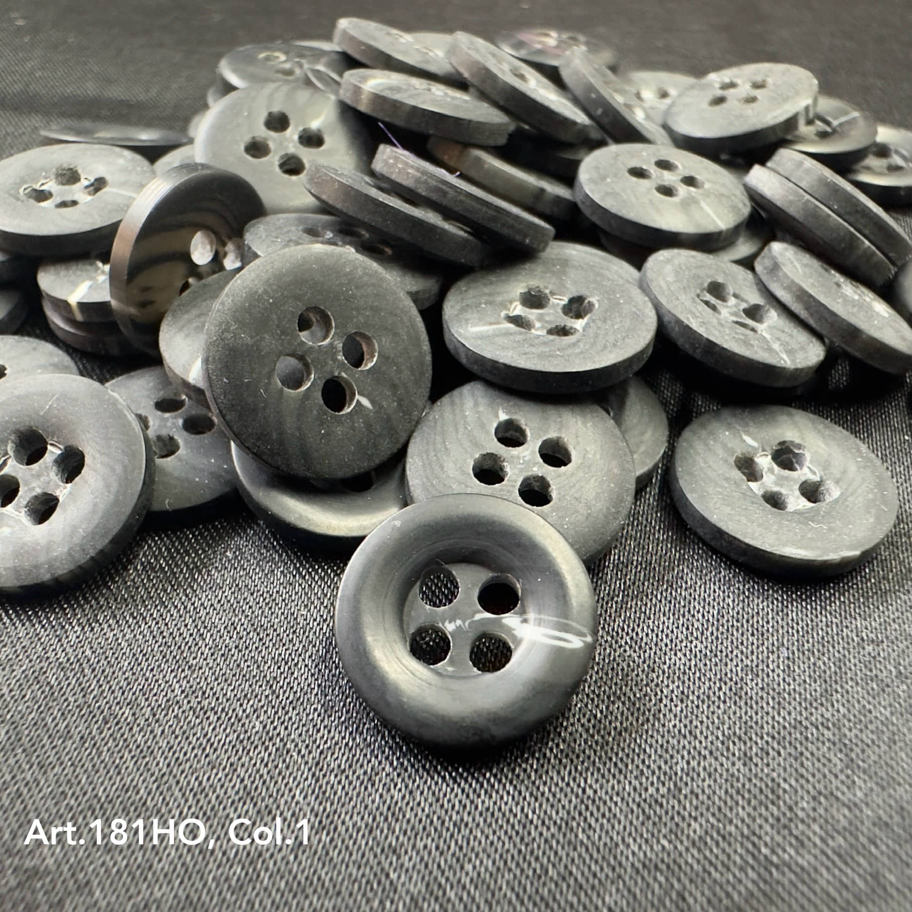 Black polyester resin sewing supplies buttons with four holes from Buttonology Inc. on fabric surface