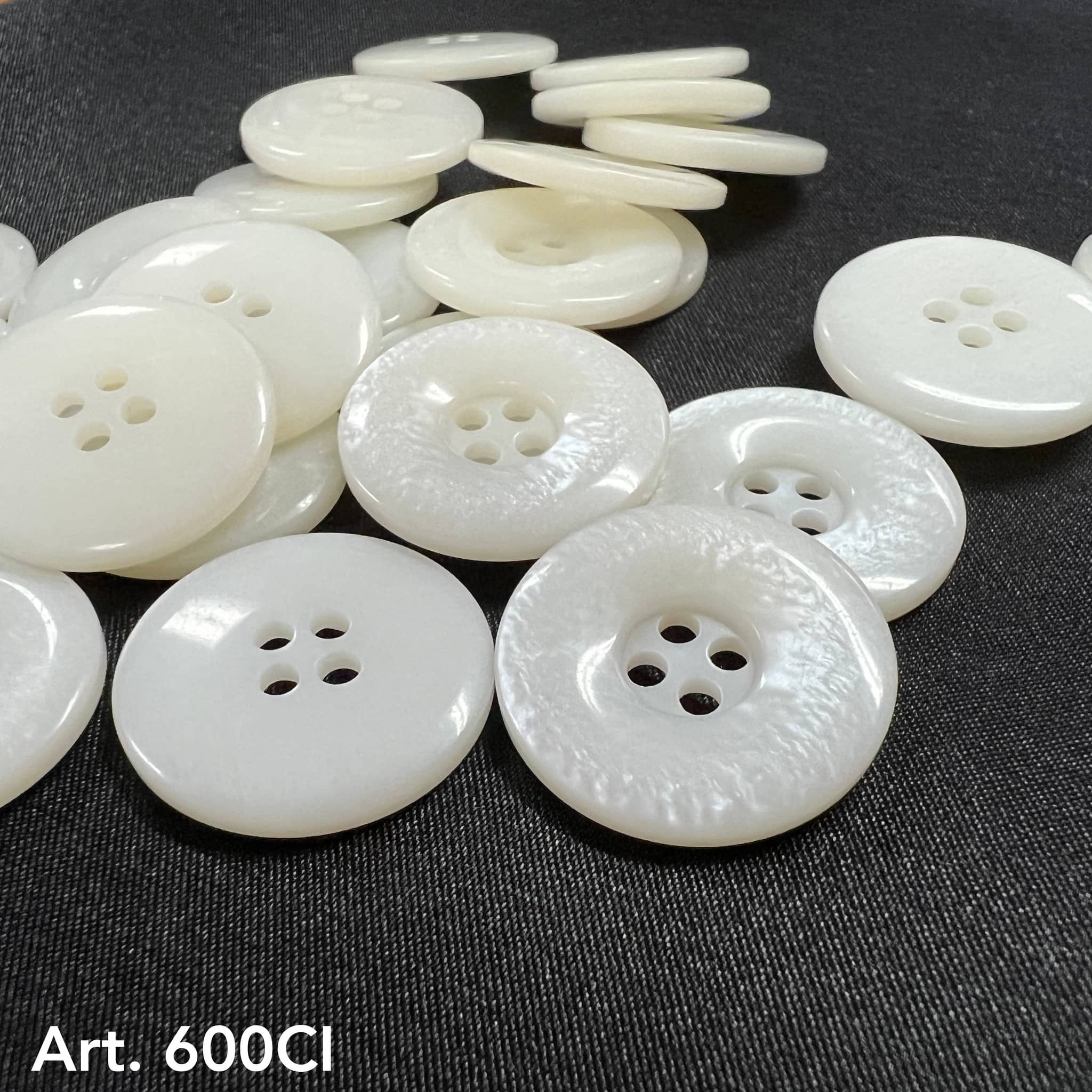 High-quality white buttons from Buttonology Inc scattered on black fabric background