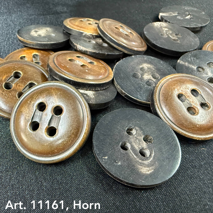 Large horn buttons for coats in brown and black from Buttonology Inc scattered on fabric