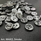 Buttonology Inc smoke marbled round 2-hole plastic buttons for DIY projects scattered on black fabric