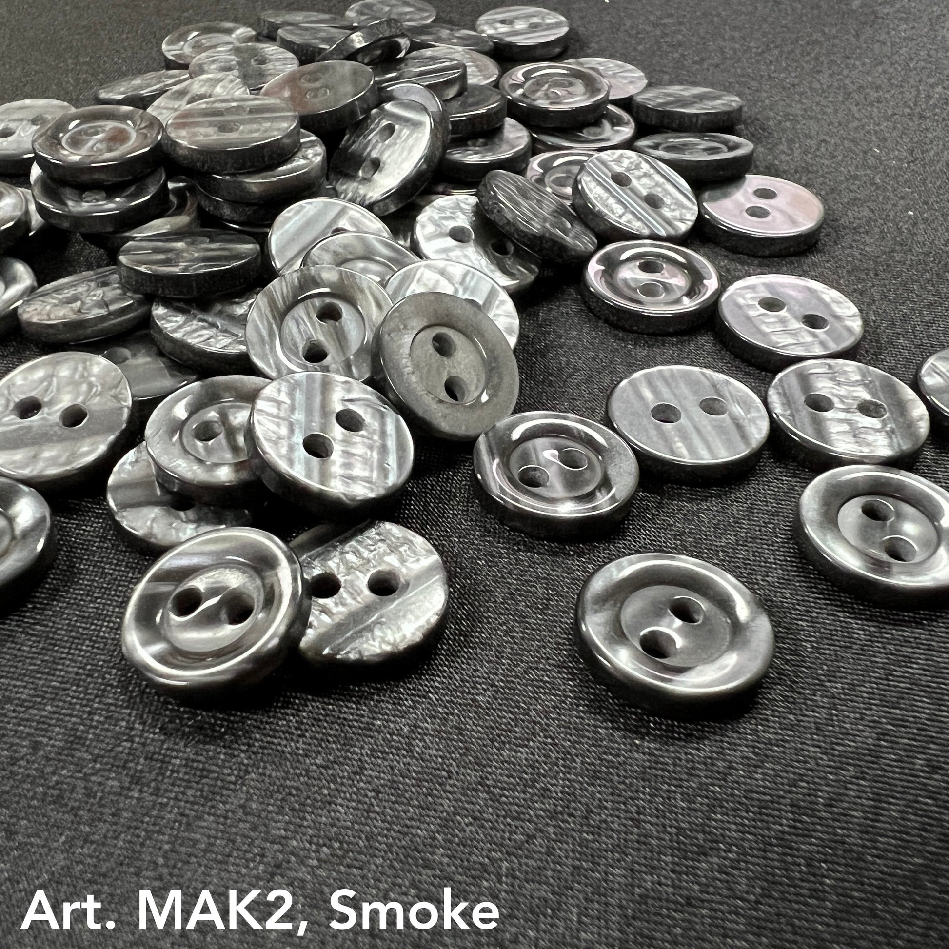 Buttonology Inc smoke marbled round 2-hole plastic buttons for DIY projects scattered on black fabric