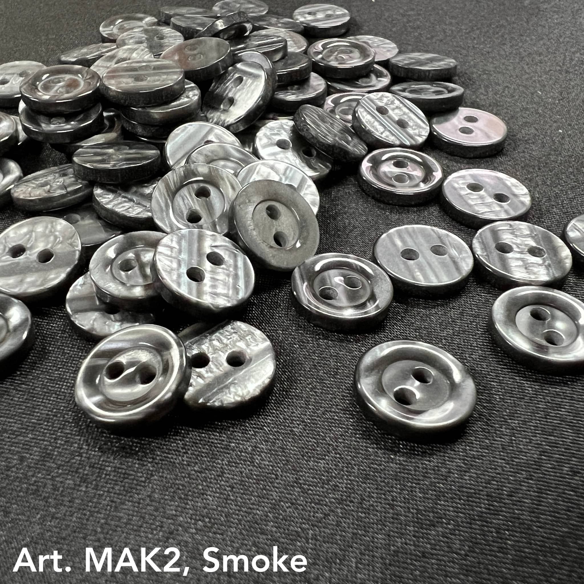Buttonology Inc smoke marbled round 2-hole plastic buttons for DIY projects scattered on black fabric
