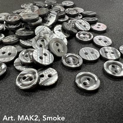 Buttonology Inc smoke marbled round 2-hole plastic buttons for DIY projects scattered on black fabric