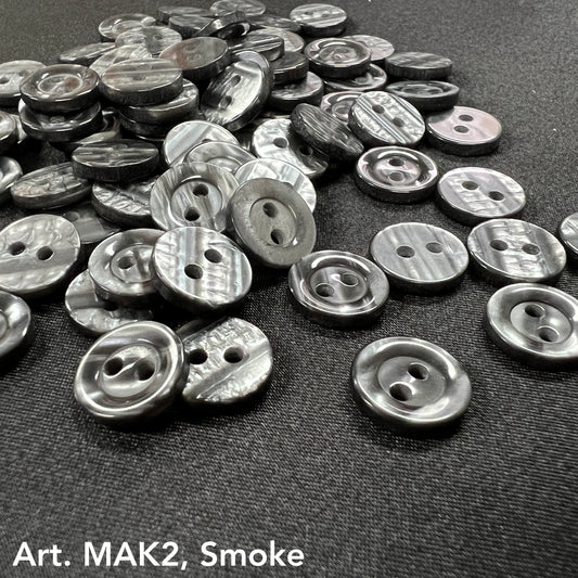 Buttonology Inc smoke marbled round 2-hole plastic buttons for DIY projects scattered on black fabric