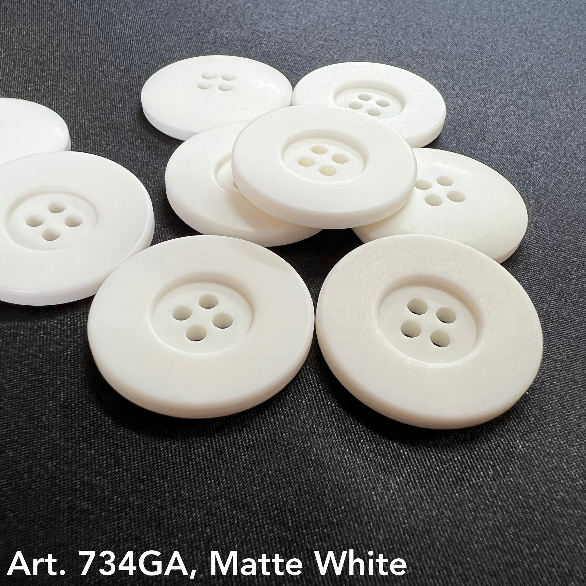 Set of matte white garment buttons in various sizes with four holes for sewing and crafting projects