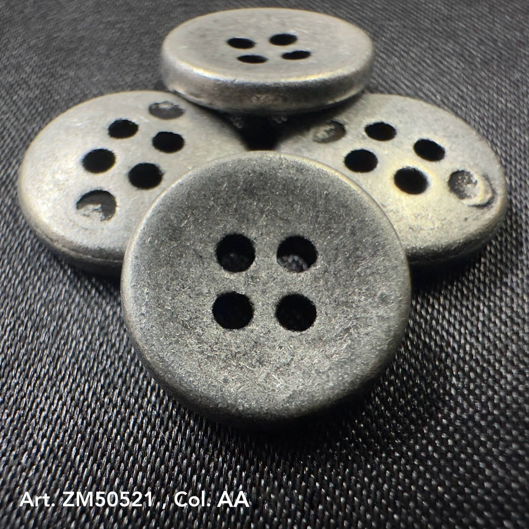 Set of four round metal buttons for clothes with a matte finish and four holes on dark fabric
