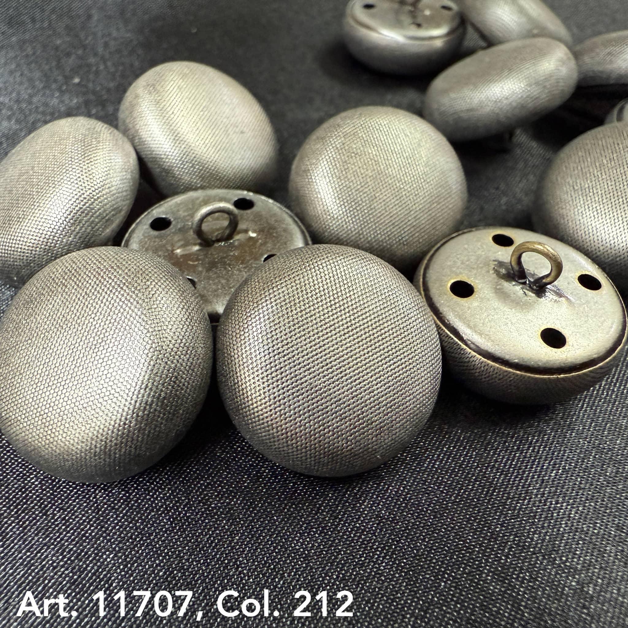 Metal dome buttons for coats with textured silver finish from Buttonology Inc close-up on dark fabric