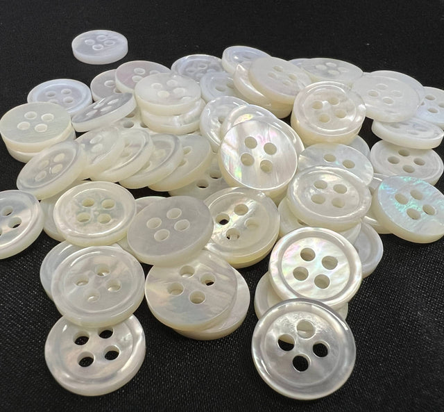 Close-up of white mother of pearl buttons by Buttonology Inc with four holes on black background