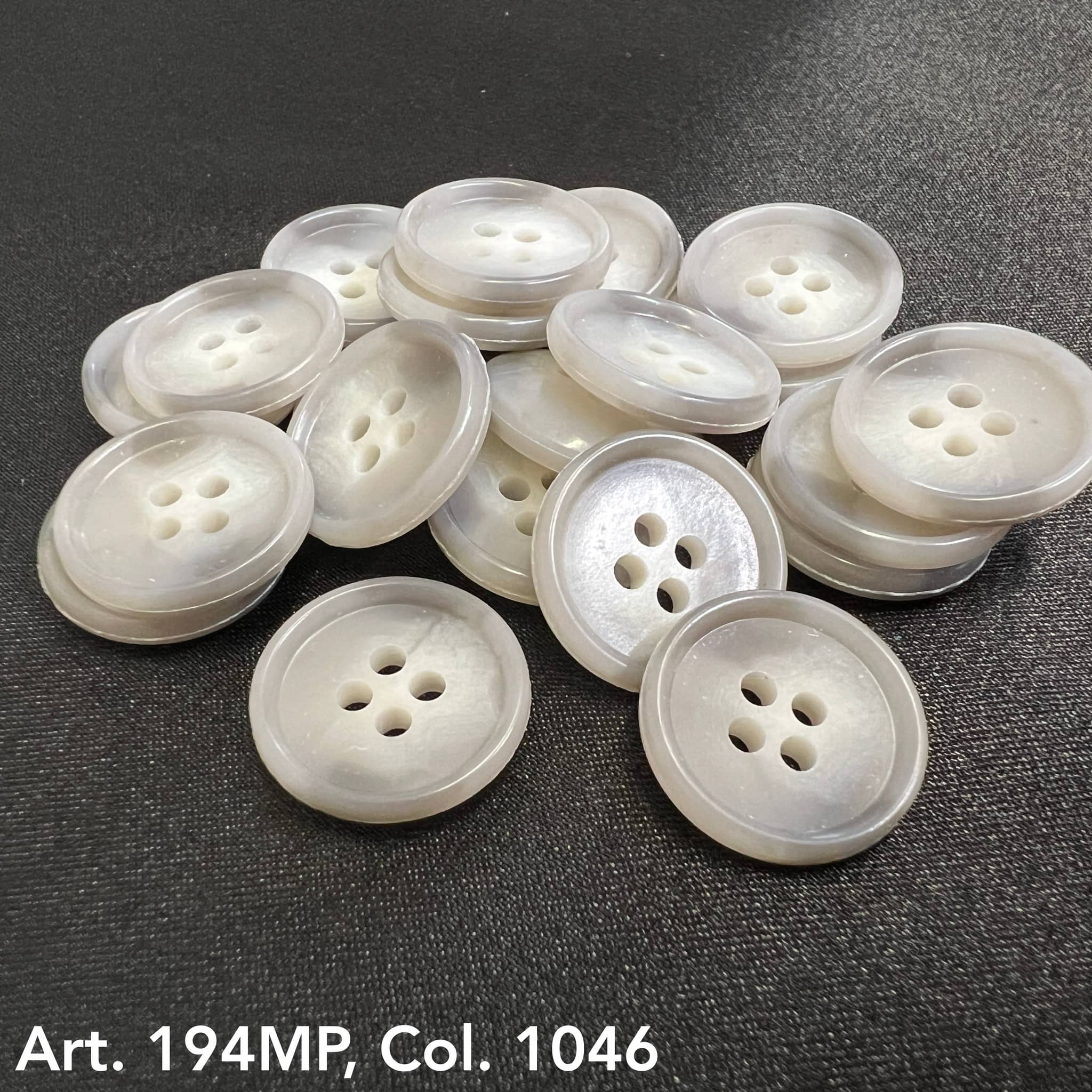 Premium suit buttons by Buttonology Inc in a stack with a glossy white finish and four holes each
