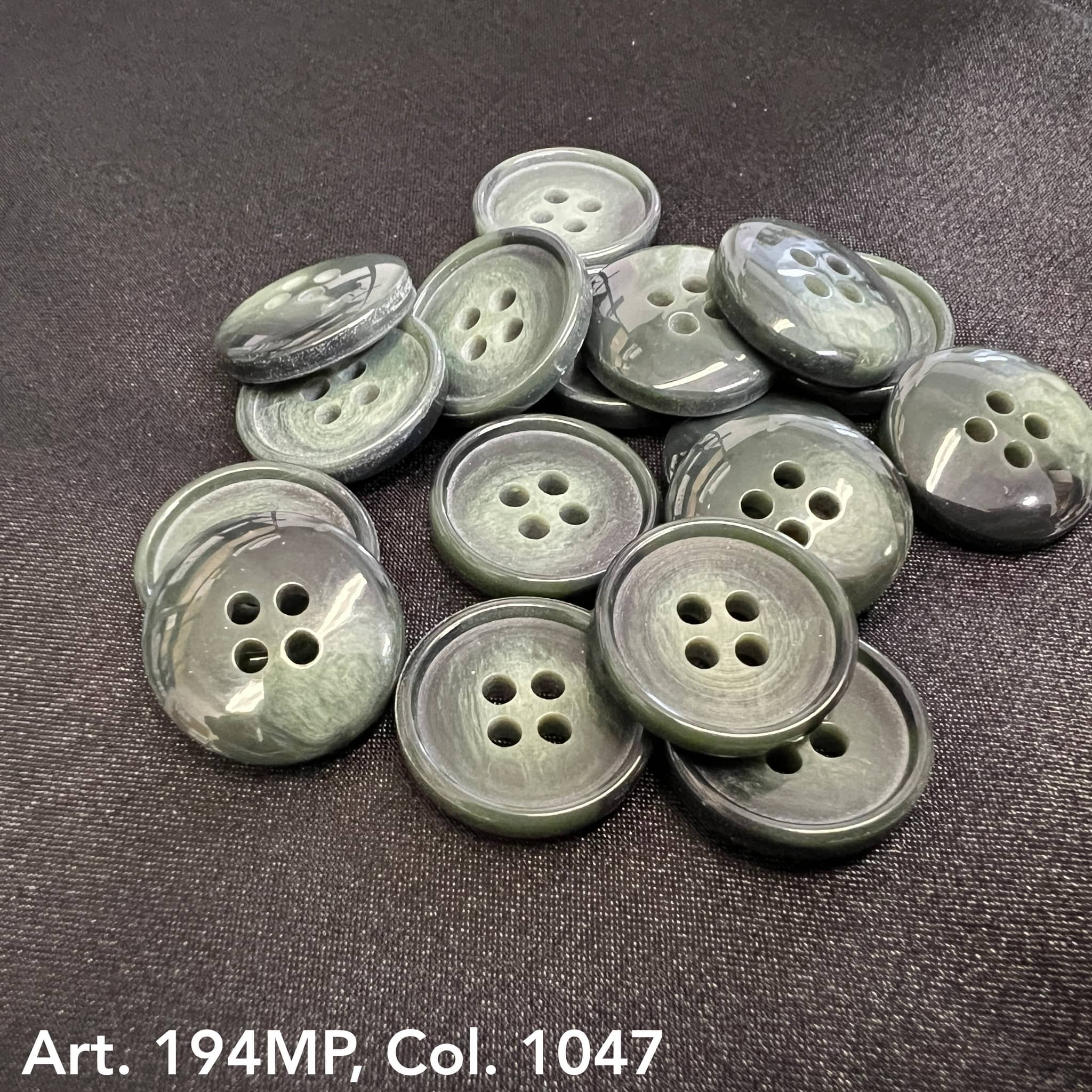 Buttonology Inc premium suit buttons in glossy dark gray with four holes laid on black fabric