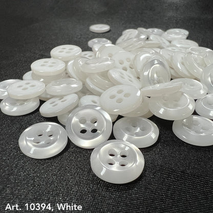 Premium white buttons for crafts by Buttonology Inc scattered on a dark fabric background