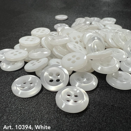 Premium white buttons for crafts by Buttonology Inc scattered on a dark fabric background