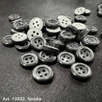 Black and white sewing accessory buttons from Buttonology Inc scattered on a dark fabric background