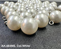 White pearl shank buttons for garments by Buttonology Inc displayed on black fabric