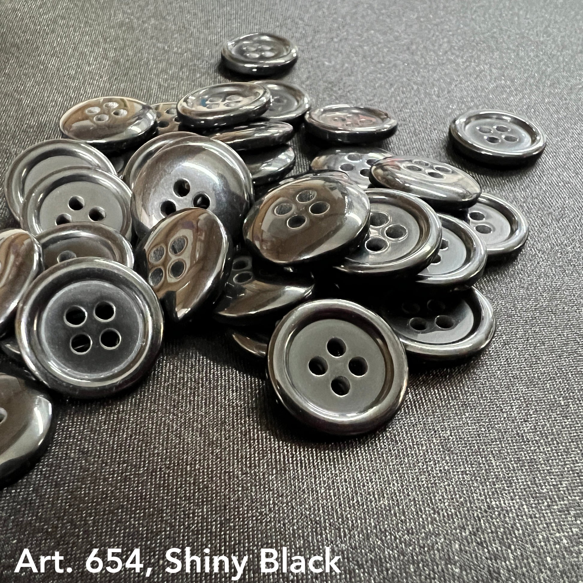 Shiny black 4-hole sewing buttons in a pile, perfect for various sewing projects