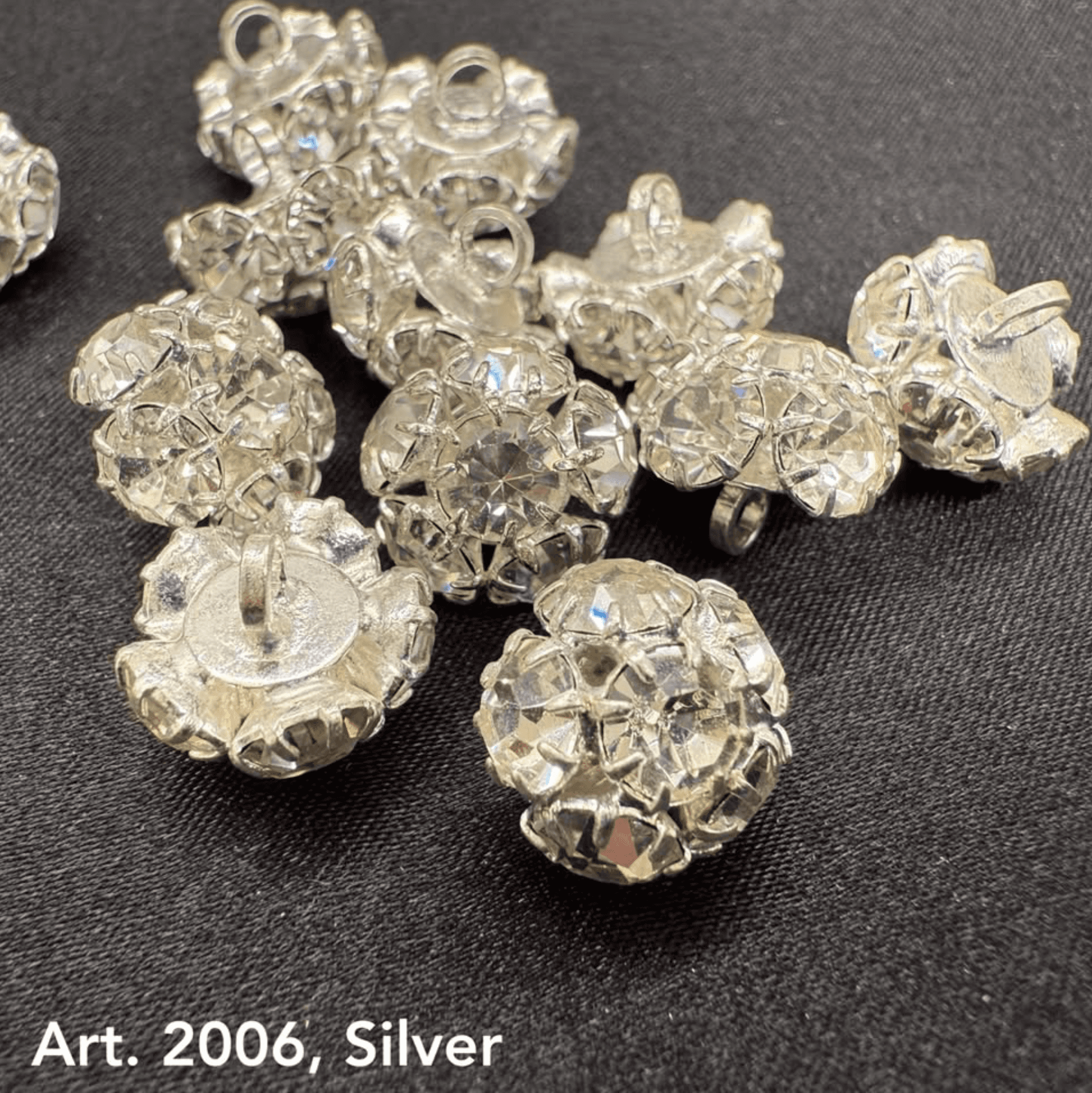 Buttonology Inc silver rhinestone buttons with sparkling faceted design on black fabric background