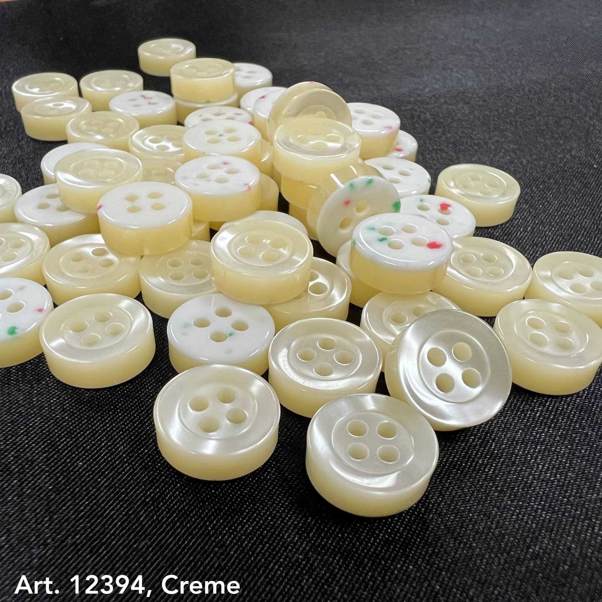 Smoke gray garment buttons by Buttonology Inc in cream color with four holes for sewing on fabric