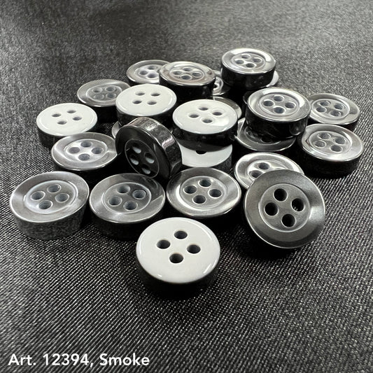 Smoke gray garment buttons in various shades and sizes from Buttonology Inc on dark fabric background