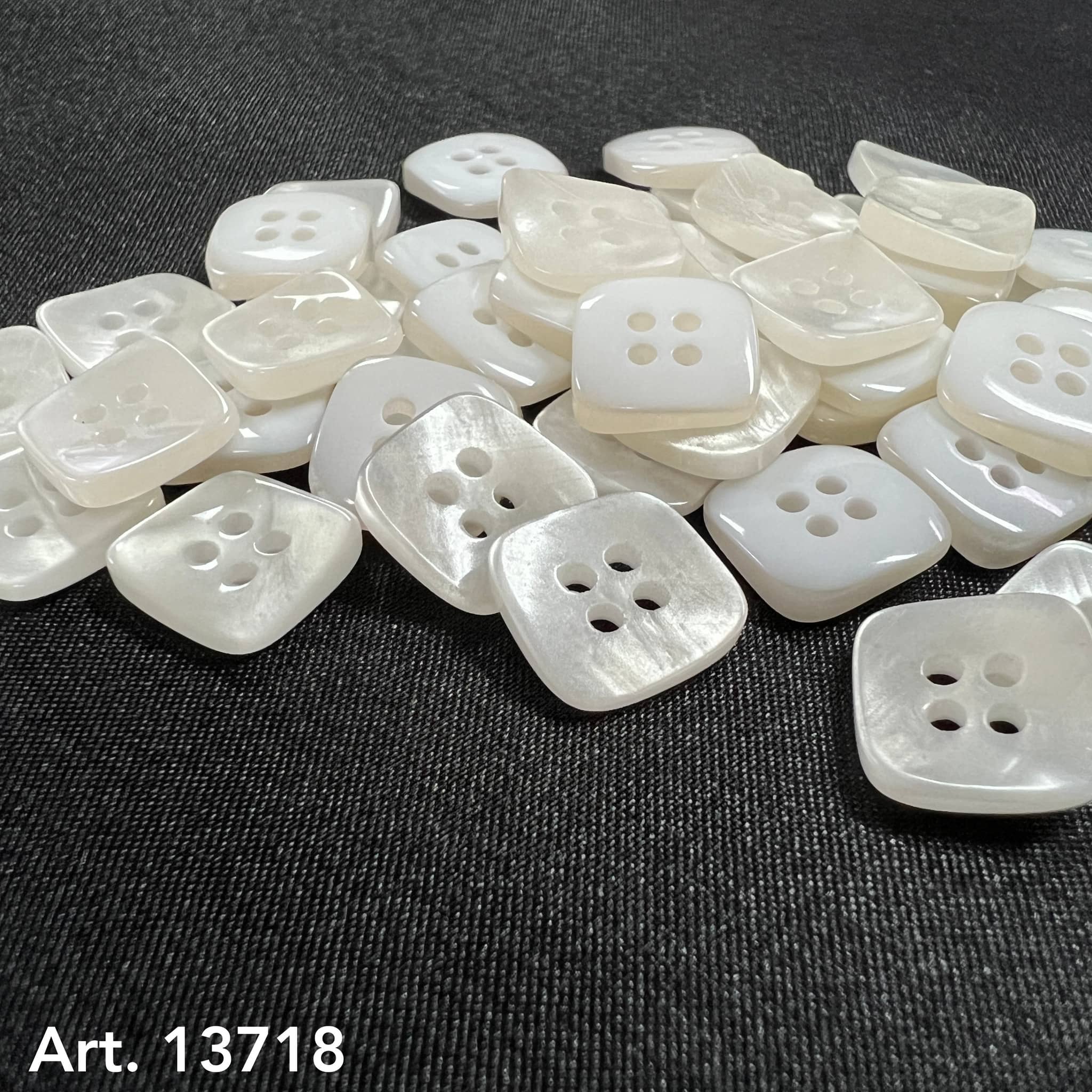 Square Shaped Sewing Buttons in white pearl finish scattered on black fabric background