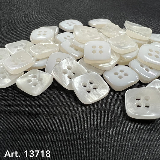 Square Shaped Sewing Buttons in white pearl finish scattered on black fabric background