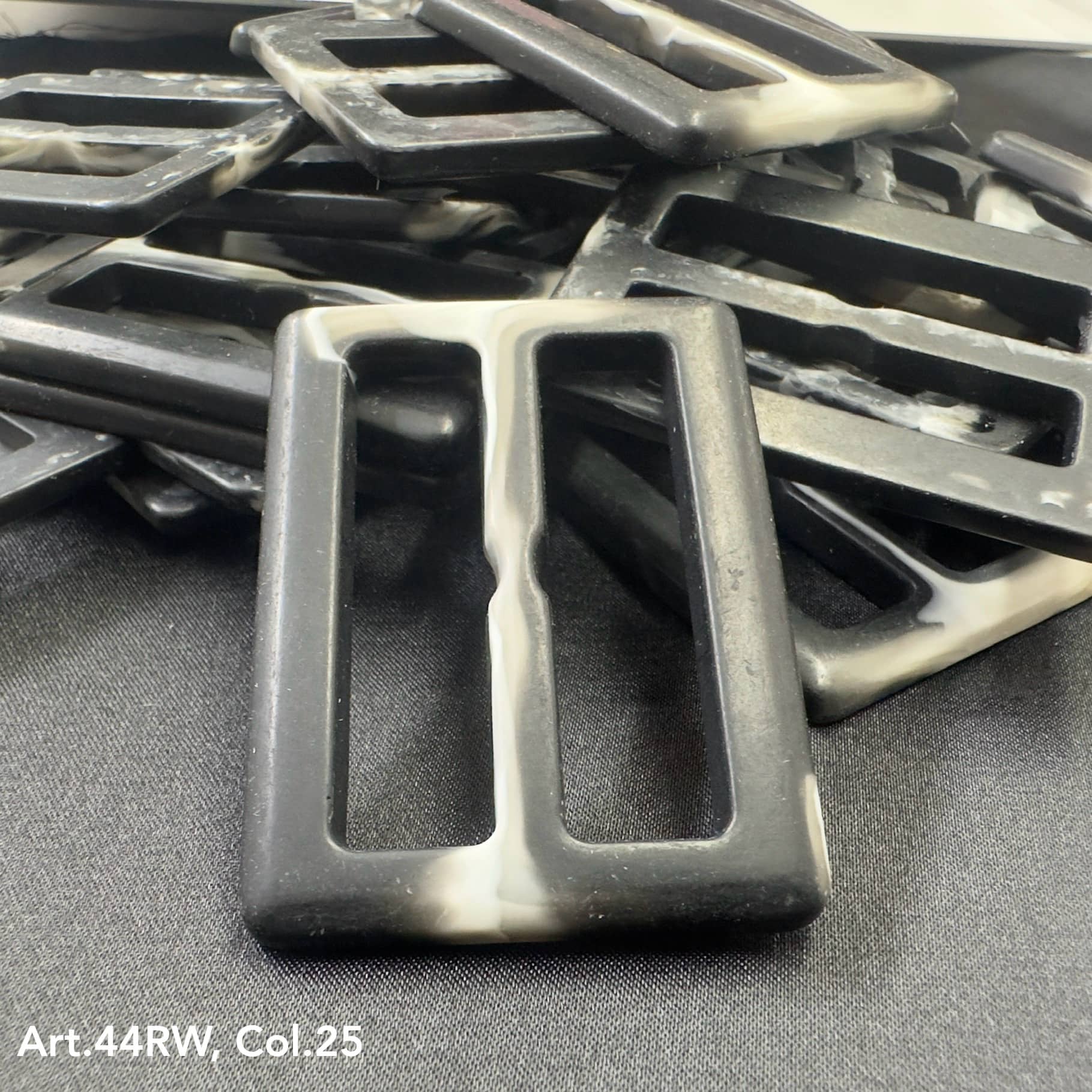 Black and white strong polyester buckles from Buttonology Inc arranged on a black surface