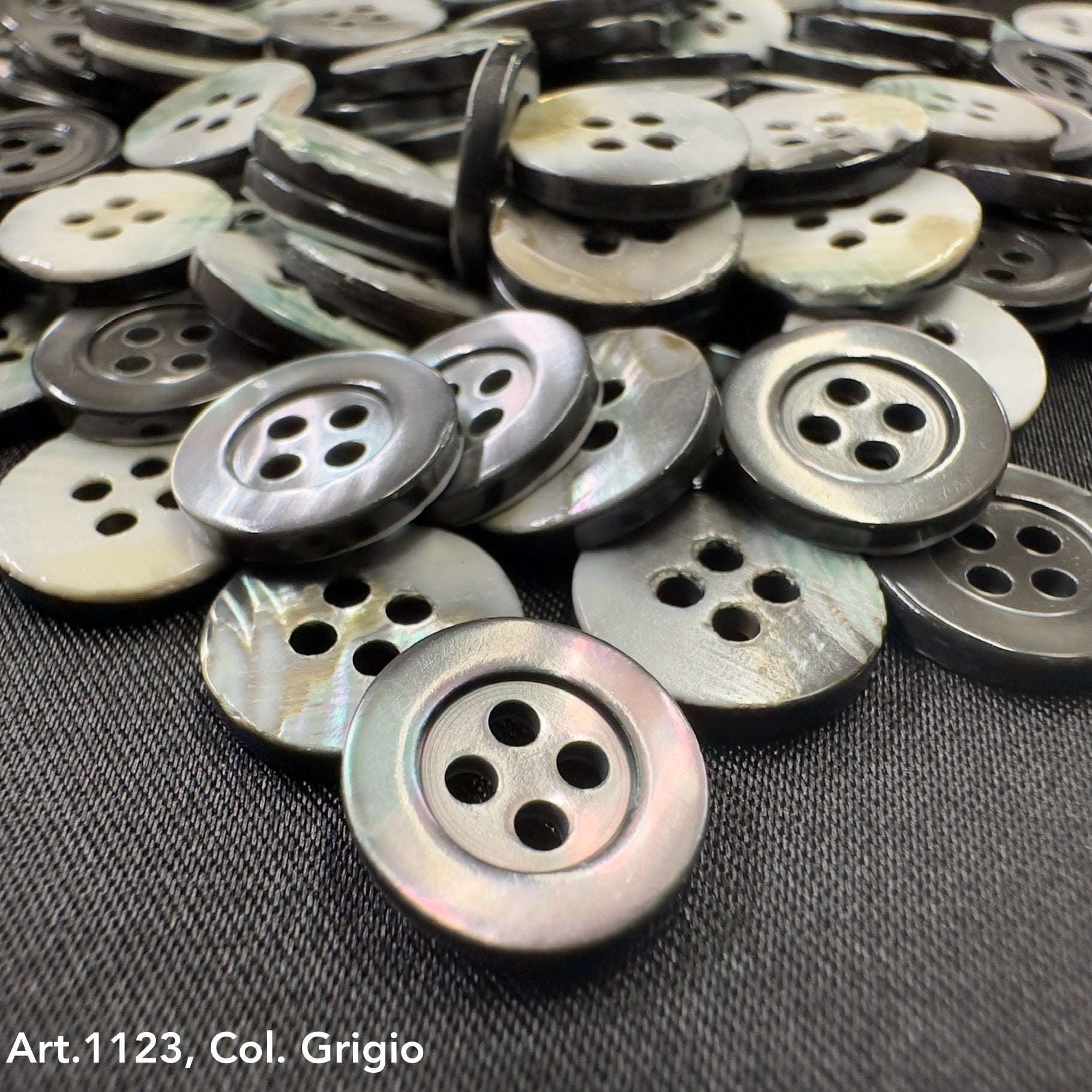 Troca shell buttons by Buttonology Inc in various shades of gray with four holes on black fabric