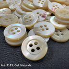 Troca shell buttons by Buttonology Inc in natural color with four holes on dark fabric background