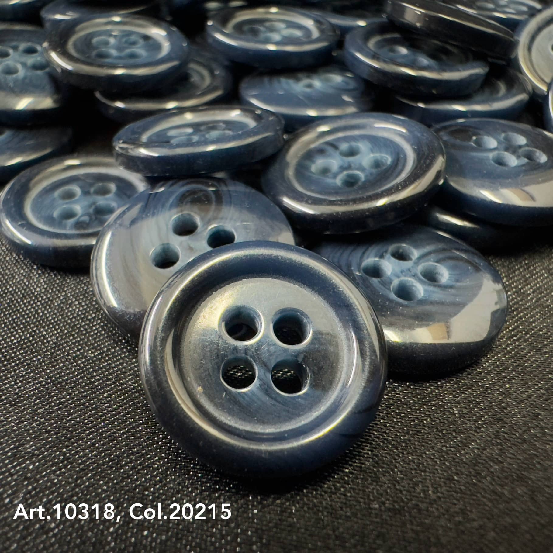 Glossy dark blue suit and coat buttons with four holes arranged on black fabric