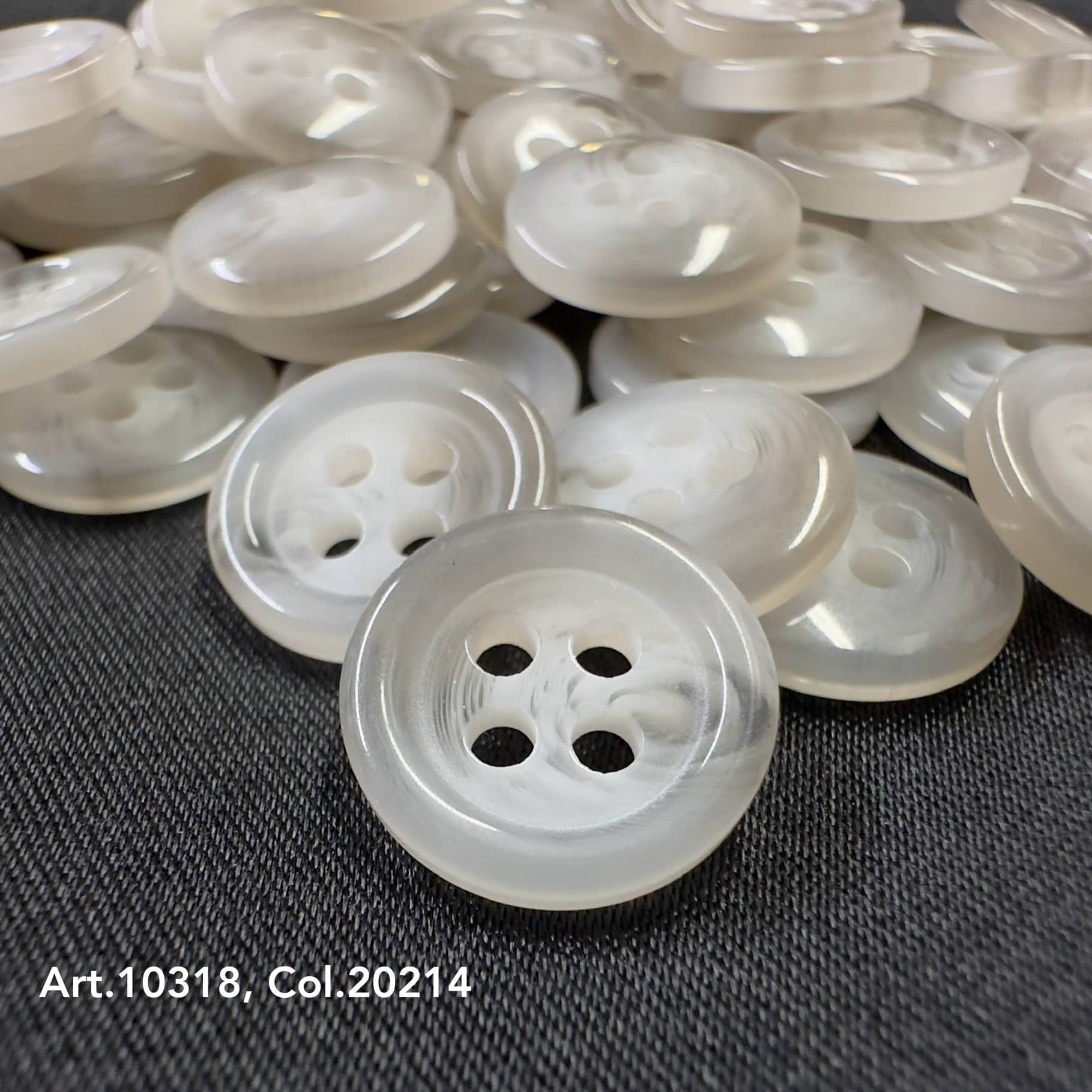 Clear round suit and coat buttons with four holes on black fabric background by Buttonology Inc
