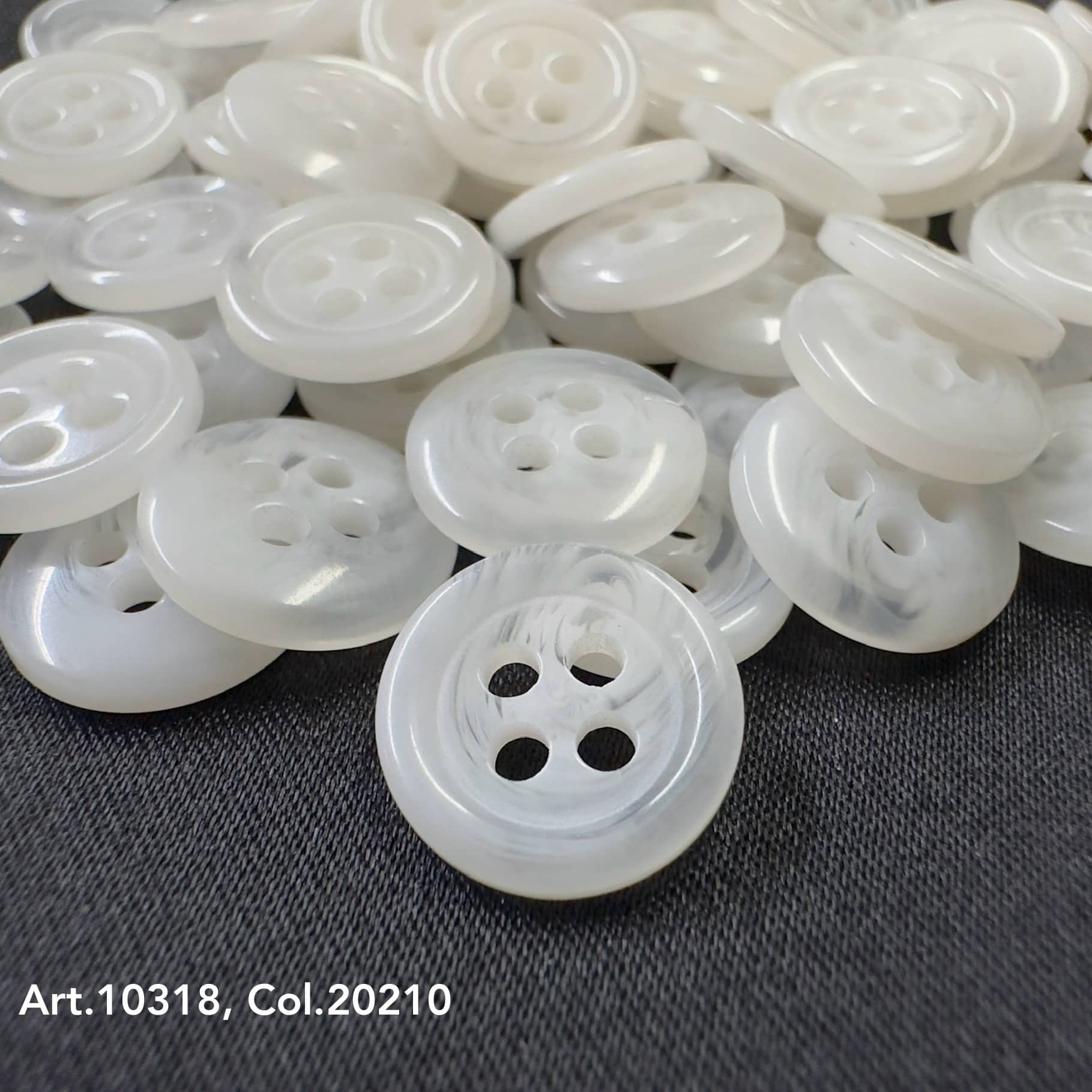 White round suit and coat buttons with four holes from Buttonology Inc on dark fabric background
