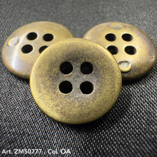 Set of three vintage metal buttons with four holes on a dark fabric background by Buttonology Inc