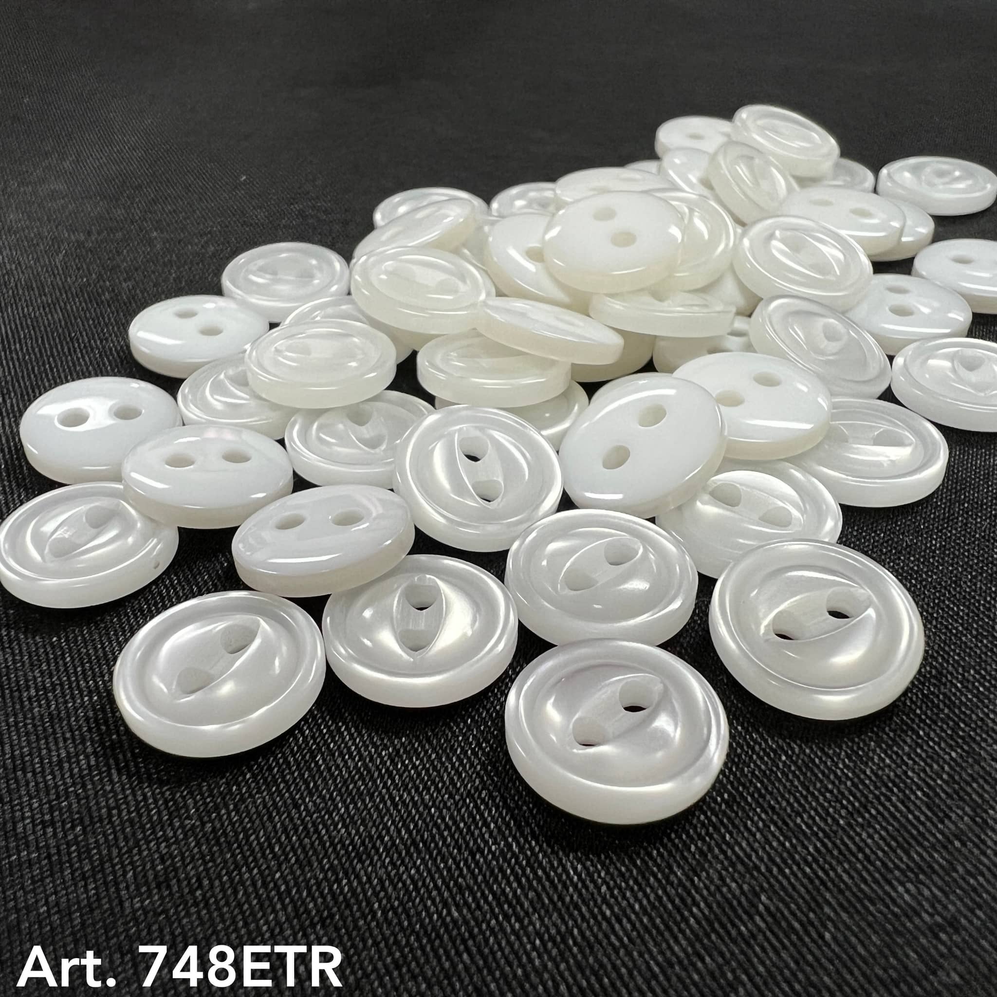 Collection of white pearl garment buttons in various sizes and styles for sewing projects
