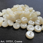 White sewing buttons for sale by Buttonology Inc in creamy white color on black fabric background