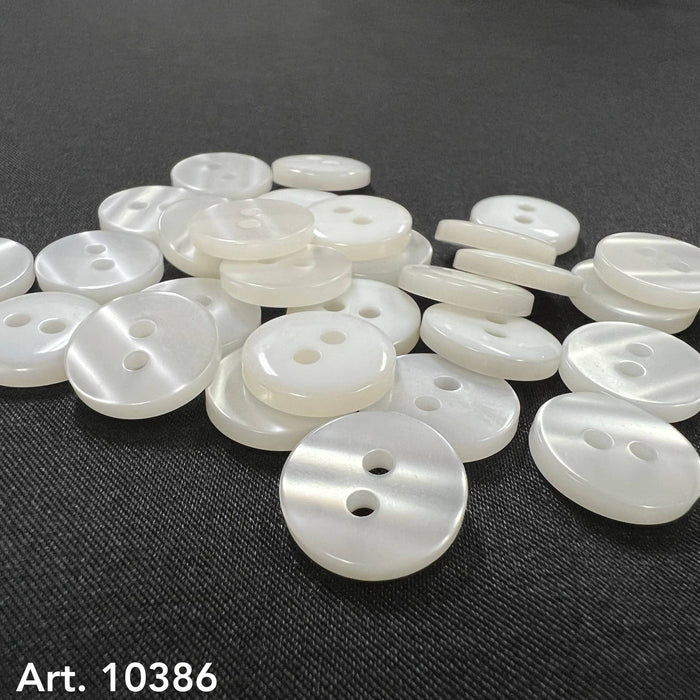 Assorted white two hole sewing buttons on a black background from Buttonology Inc