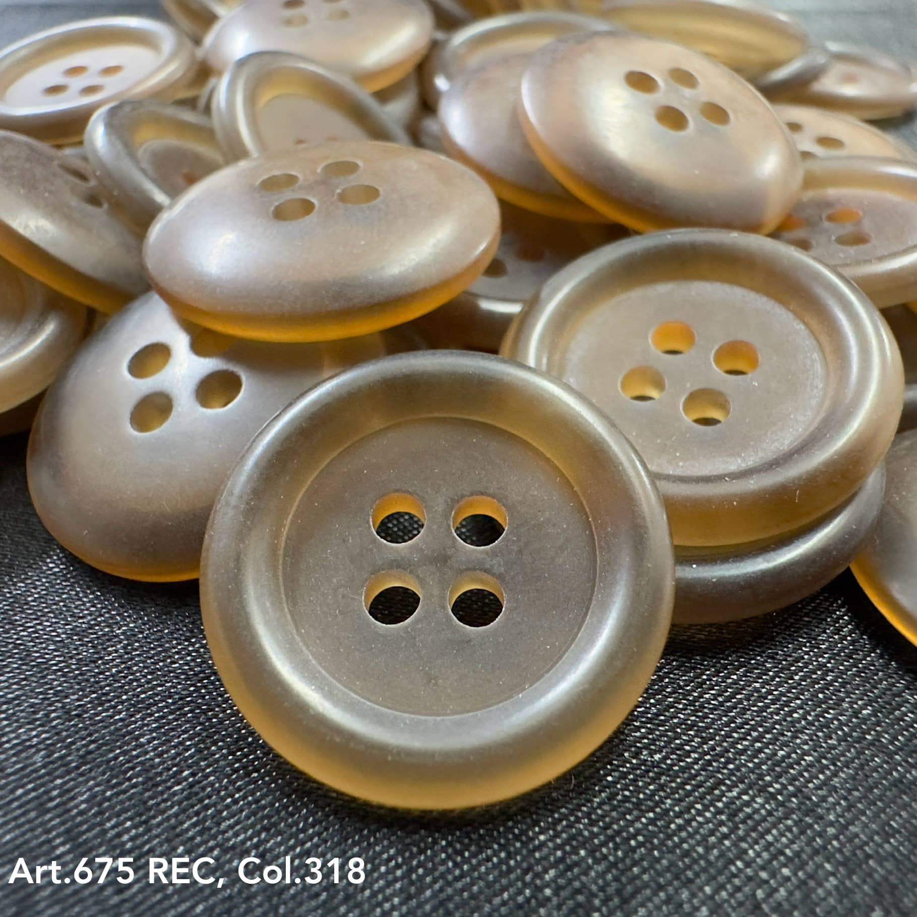 Wholesale four-hole buttons by Buttonology Inc in a translucent amber color on black fabric